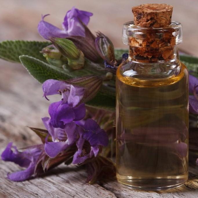Clary Sage essential oil with clary sage flowers in the background